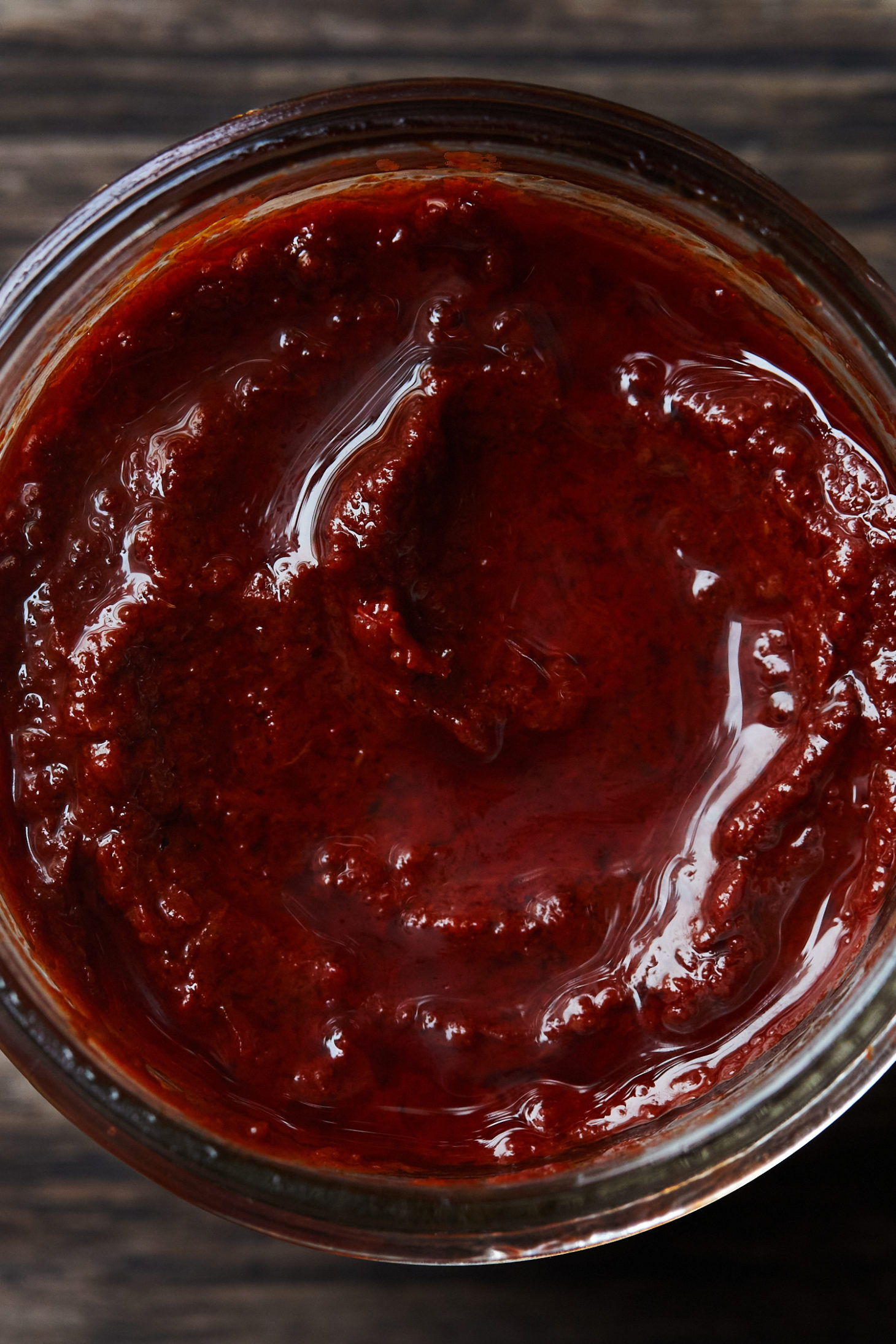 Close-up of a reddish paste in a clear jar.