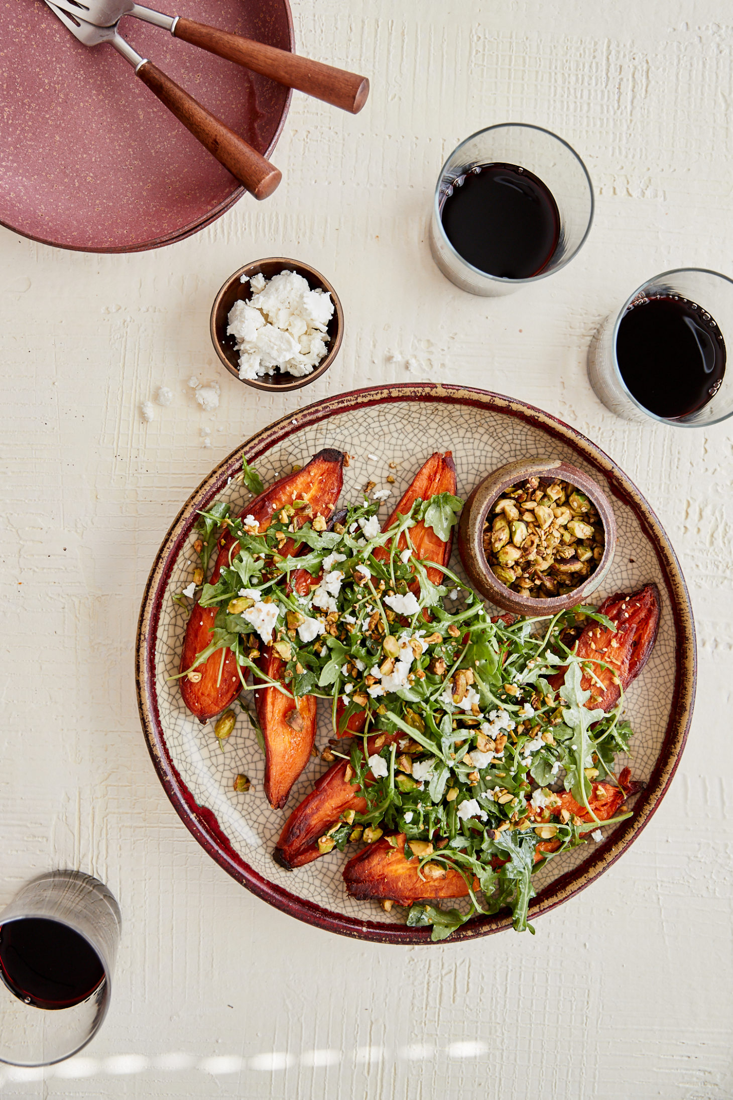 overhead image of sweet potatoes covered with arugula on a crackled large plate